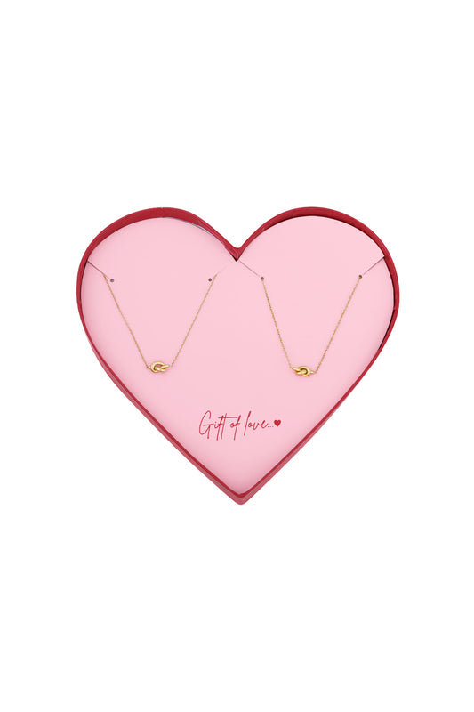 Heart-shaped gift box with soft pink interior, containing a delicate gold-tone stainless steel necklace and matching bracelet featuring a knot design