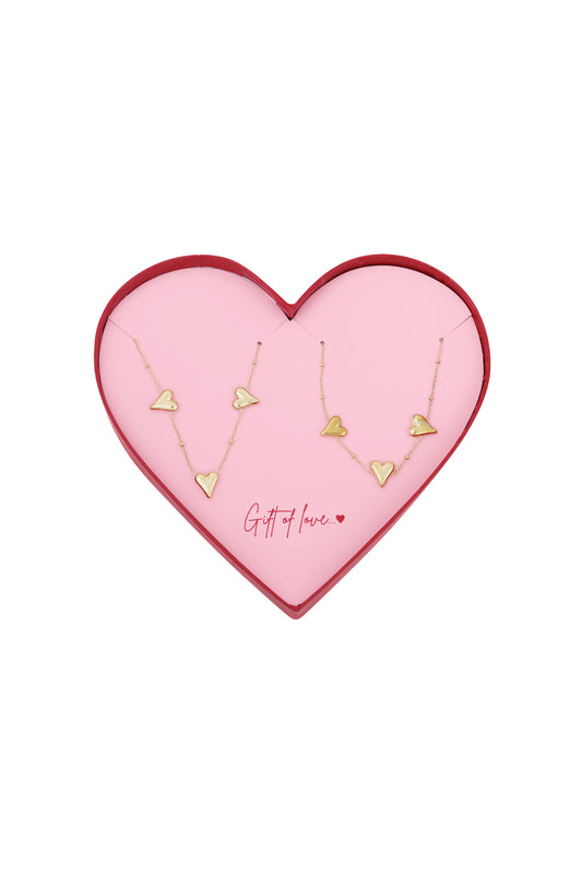 Gold-tone heart charm necklaces displayed in a pink heart-shaped gift box with red edges and the phrase 'Gift of love' inside