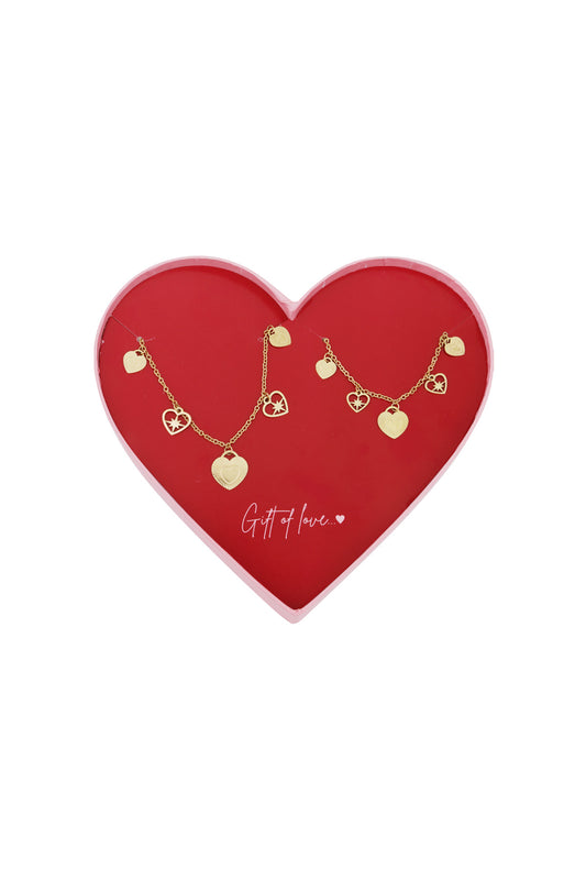 Heart-shaped red box containing two gold-tone charm bracelets with heart and star charms