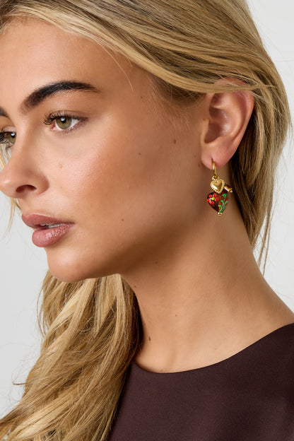 Close-up side view of woman wearing gold hoop earrings with brown floral heart charms
