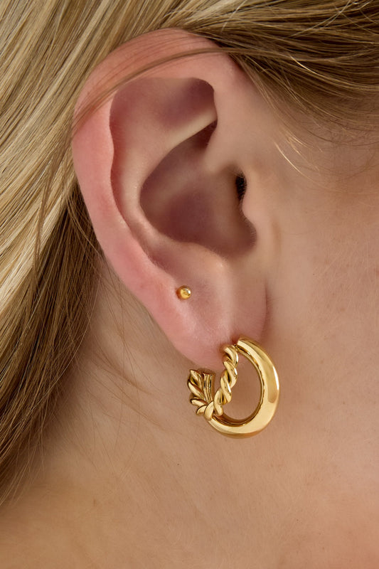 Close-up of woman wearing gold dual hoop earrings showing twisted and smooth design