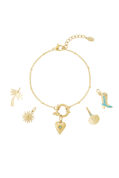 Gold chain charm bracelet with heart, palm tree, sun, shell, and boot charms laid out on white background