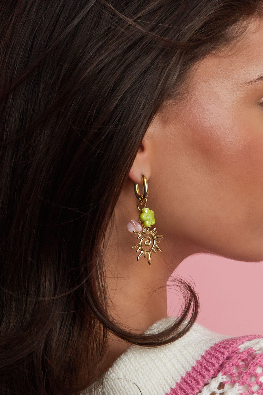 Close-up side view of model wearing gold-tone sun charm drop earrings with colorful charm details