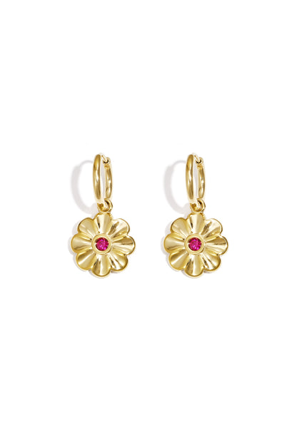 Pair of gold-tone hoop earrings each with a flower-shaped pendant featuring a central pink stone on white background