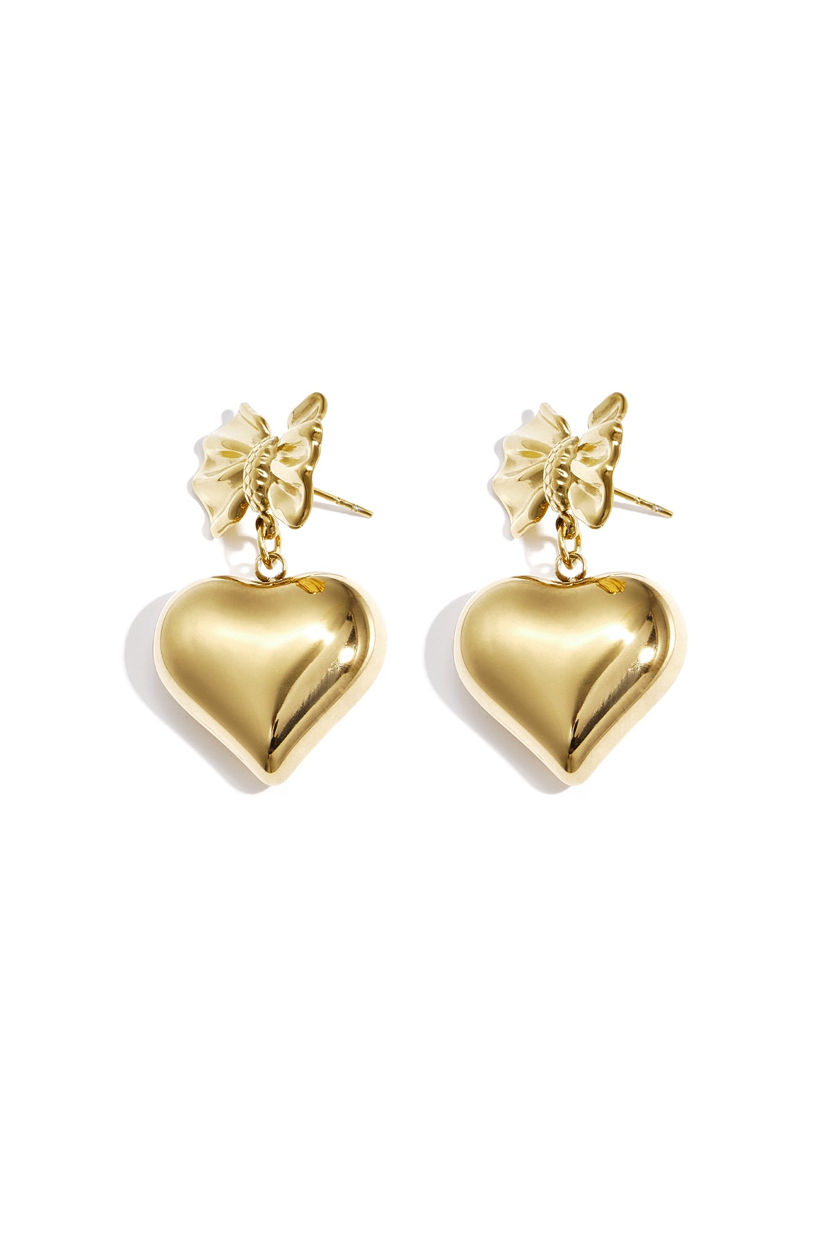 Close-up of gold dangle earrings featuring a bow knot and hanging heart charm
