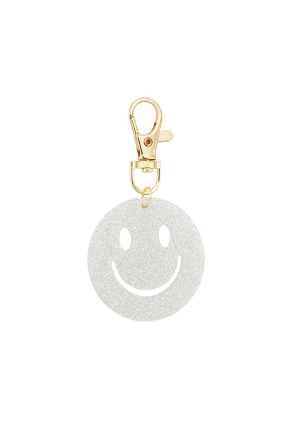 White glitter smiley face keychain with gold clasp on white background