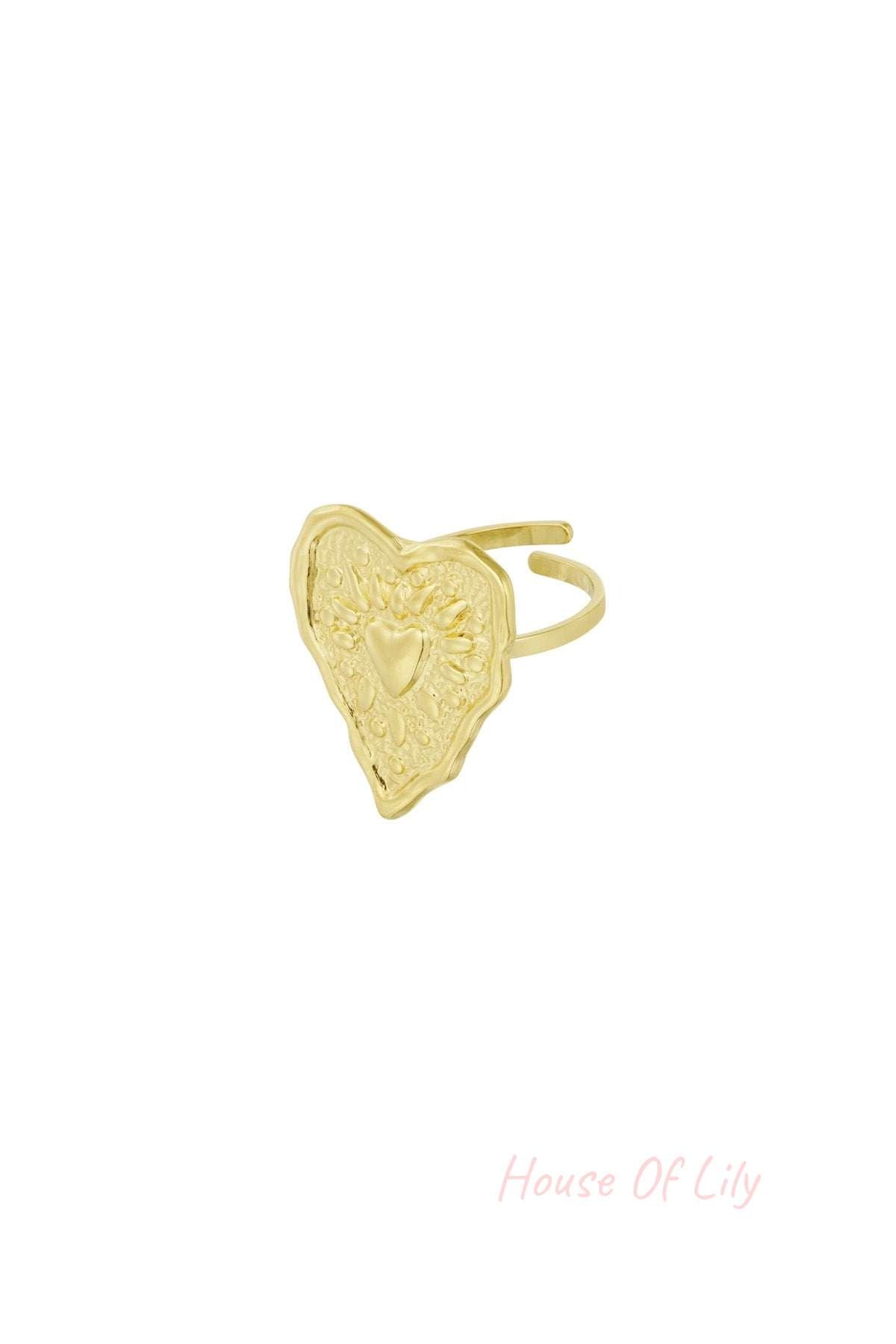 Close-up of gold stainless steel ring with wrinkled heart design and embossed details on adjustable band