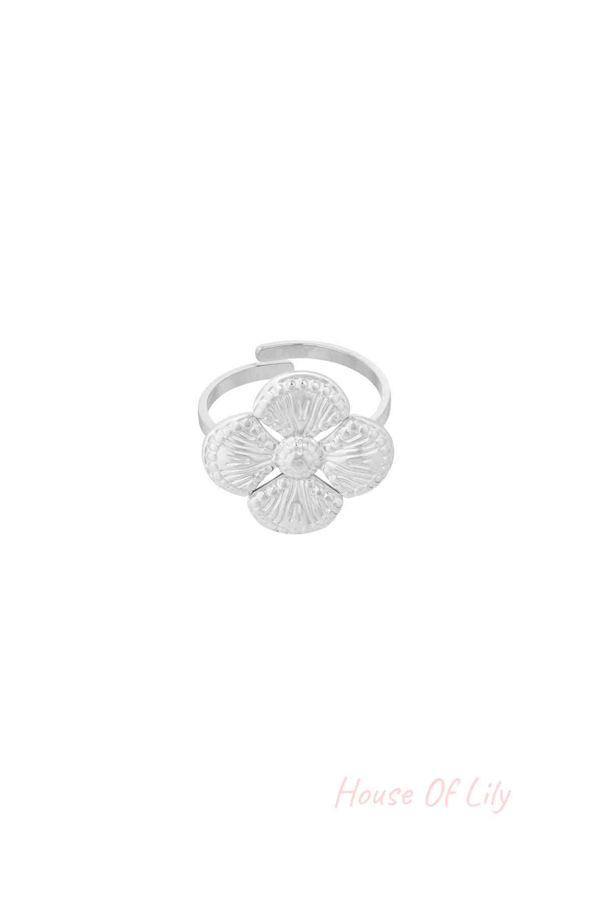 Close-up of a silver textured clover statement ring with four petals on a white background