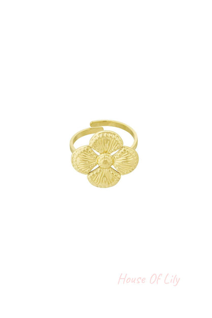 Close-up of a gold textured clover statement ring with four petals on a white background