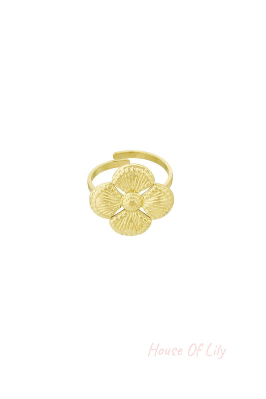 Close-up of a gold textured clover statement ring with four petals on a white background