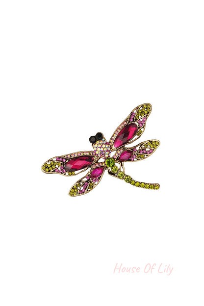 Colorful dragonfly brooch with pink and green stones set in gold-tone alloy on white background