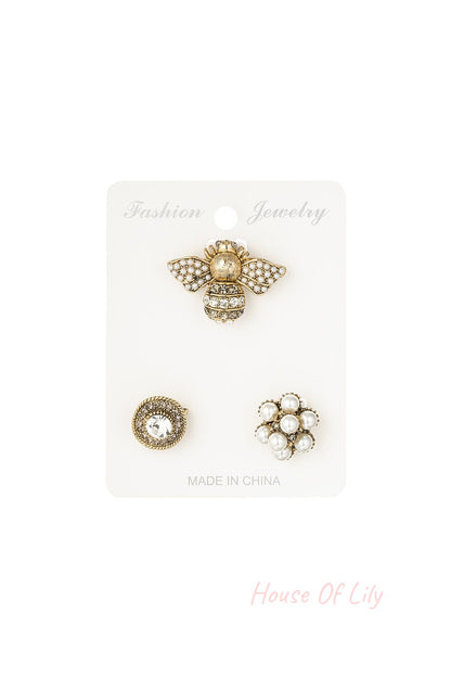 Set of three women's brooches displayed on a white backing card labeled 'Fashion Jewelry', including a pearl-studded bee, a circular rhinestone brooch, and a pearl flower cluster
