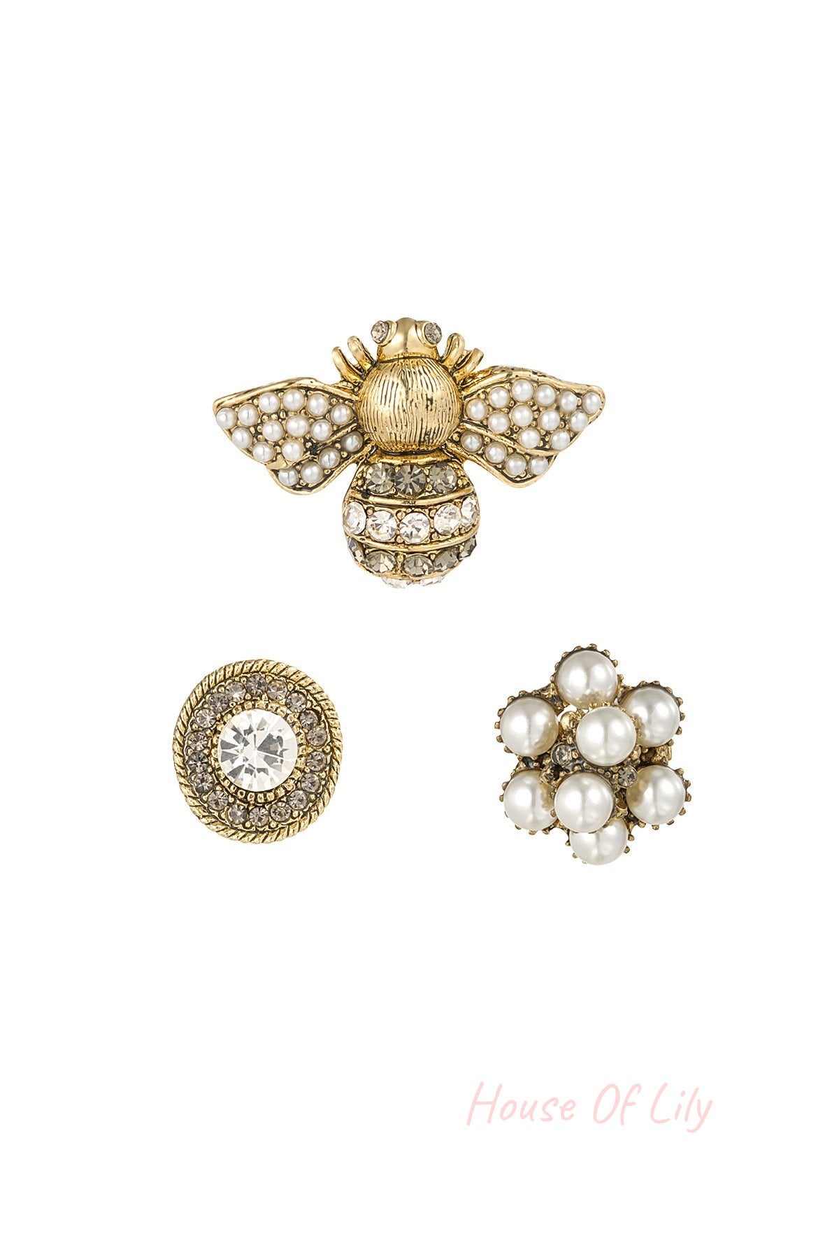 Set of three decorative women's brooches including a pearl and rhinestone bee, a circular crystal-encrusted brooch, and a pearl cluster flower on white background