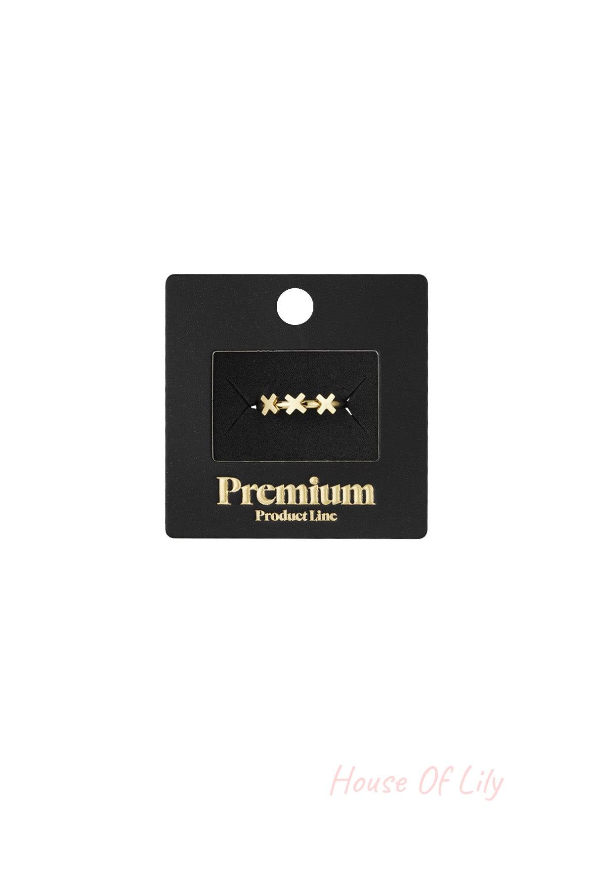 Gold triple cross ring displayed on black Premium Product Line packaging
