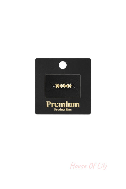 Gold triple cross ring displayed on black Premium Product Line packaging