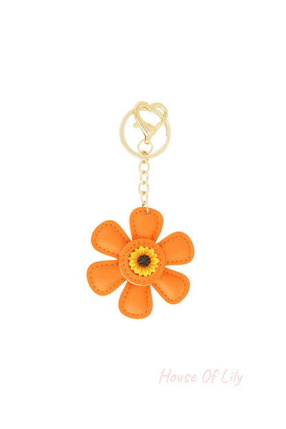 Orange faux leather floral keychain with sunflower center and gold heart clasp on white background
