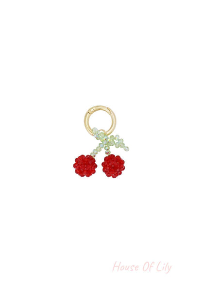 Cherry bead bag charm with red and green beads on gold-tone clasp isolated on white background