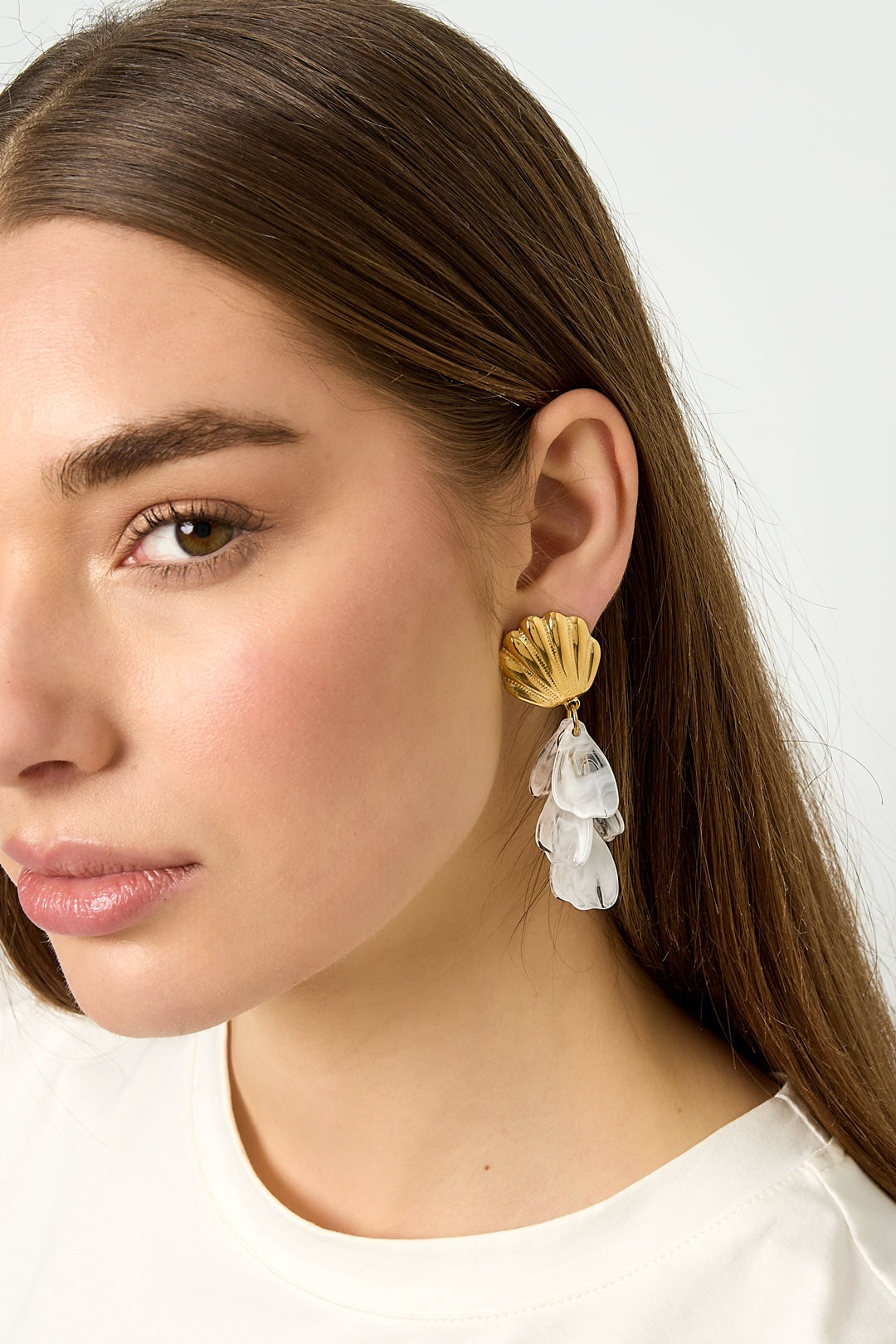 Gold shell drop earrings with dangling marbled white translucent petals on white background