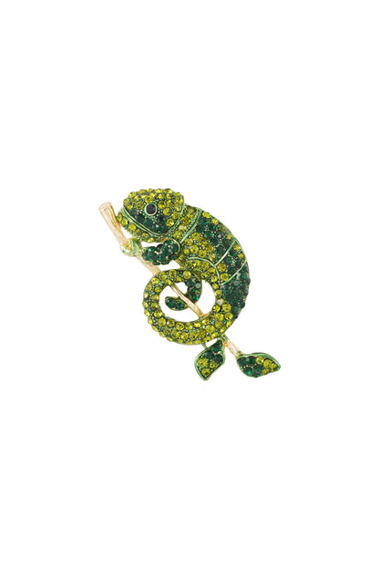 Close-up of a green rhinestone chameleon brooch with yellow and dark green stones on an alloy branch on a white background