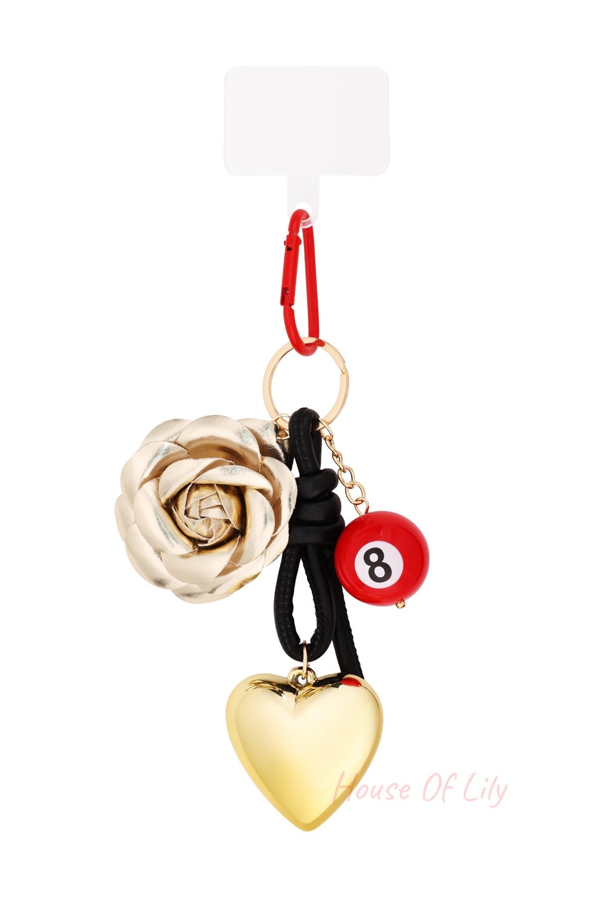 Close-up of a bag charm with a golden metallic rose, red 8-ball bead, shiny gold heart, and red carabiner clasp on a white background
