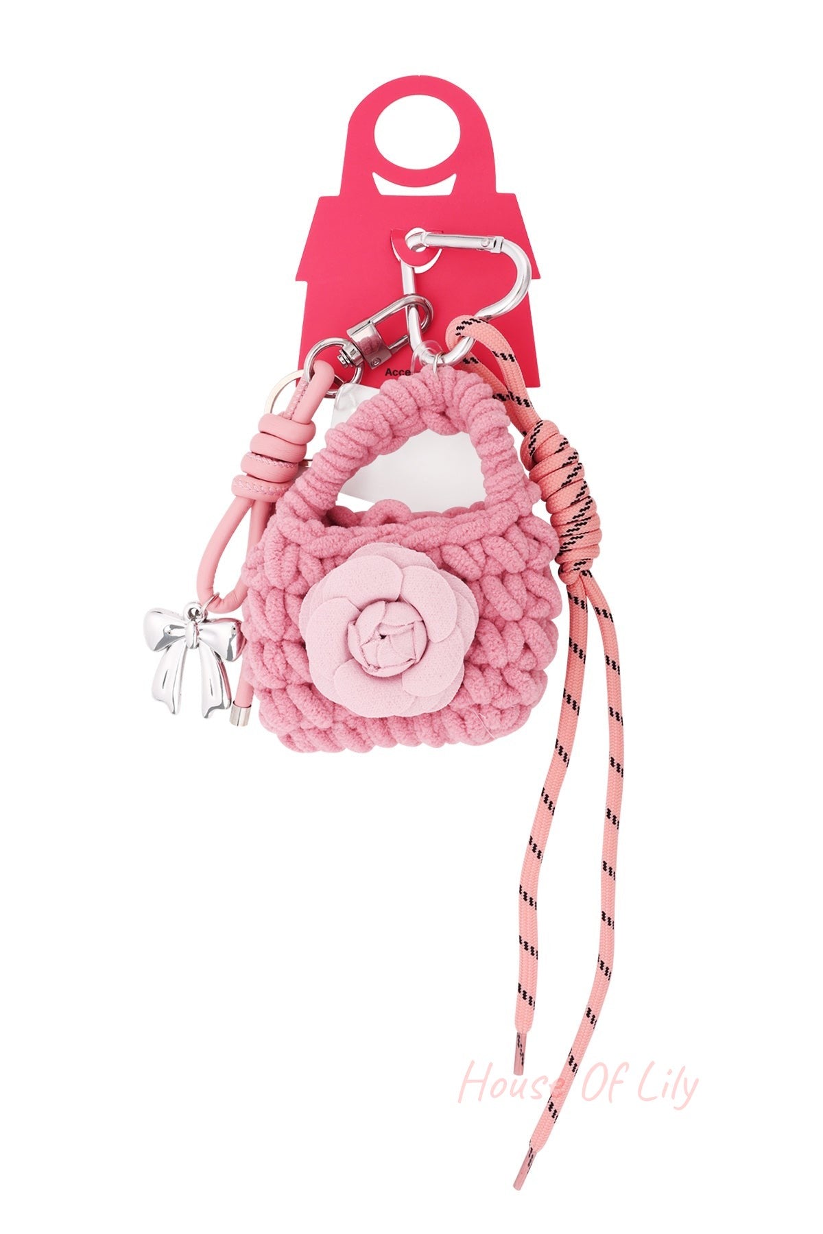 Pink knitted flower keychain with silver bow charm and pink striped cord hanging on a red display card shaped like a handbag