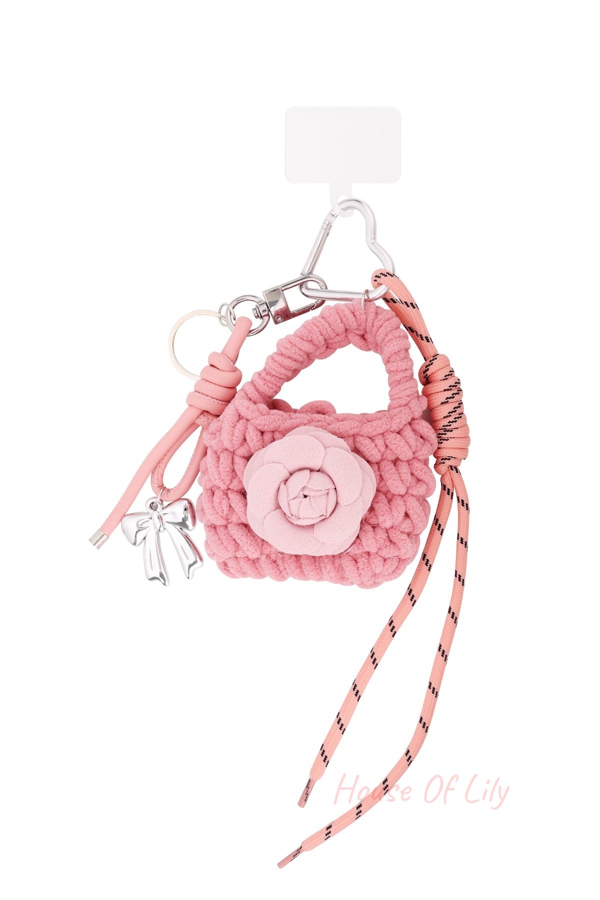 Pink knitted bag-shaped keychain with flower applique, silver bow charm, and pink cord on white background