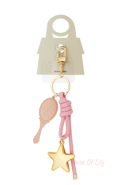 Bag charm with golden clip hook, pink knotted leather, golden star pendant and beige vintage mirror pendant shown with packaging