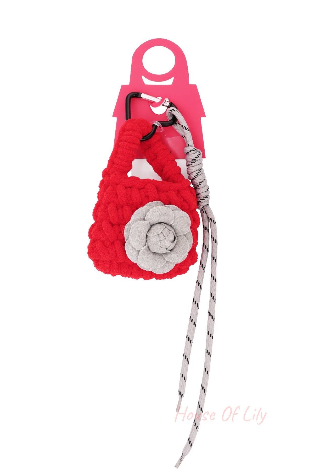 Red knit mini purse flower bag charm on a retail display card featuring a black carabiner clip and long striped white laces