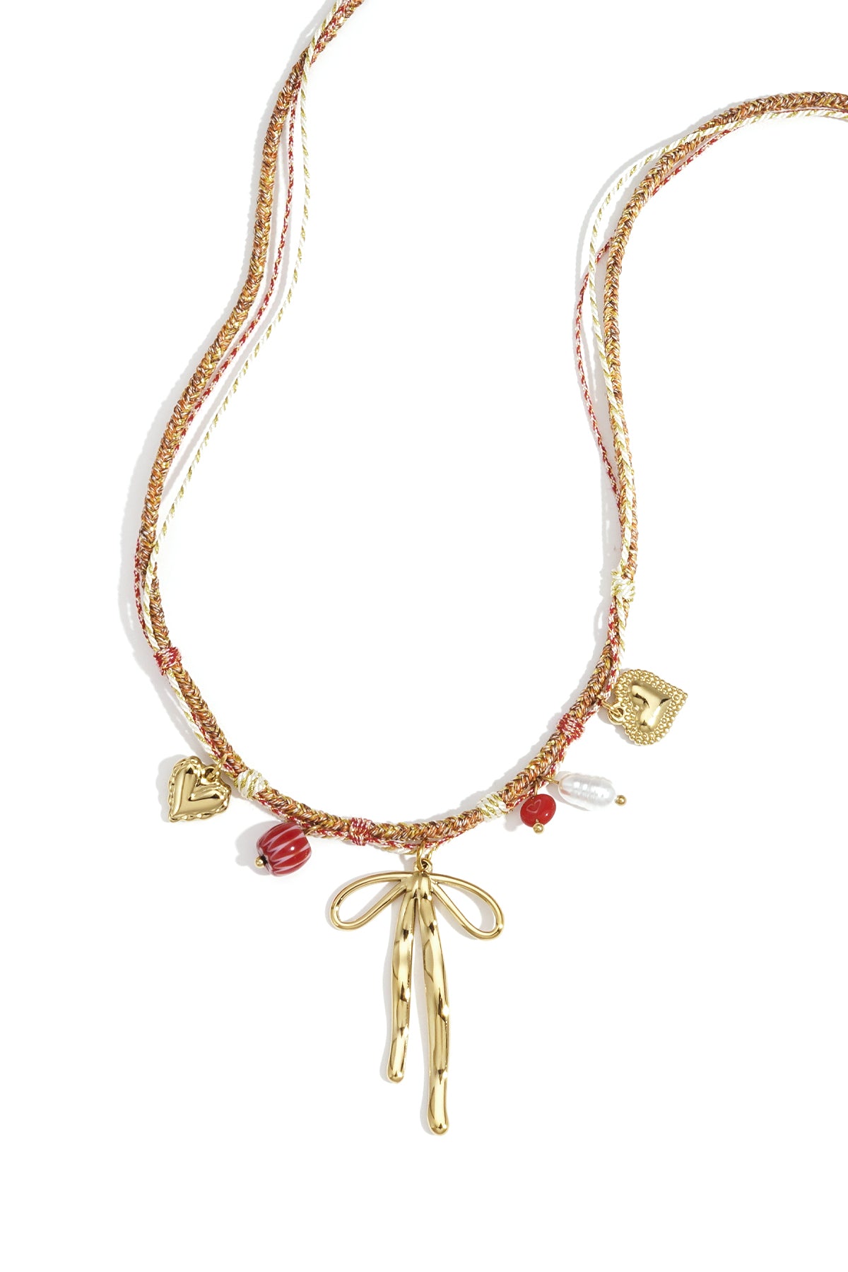 Close-up of a colorful gold-tone charm necklace with a bow pendant, heart charms, and red and white beads on braided cords