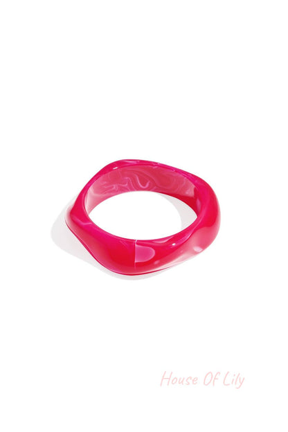 Single bright pink marbled acrylic wavy square bangle on a white background