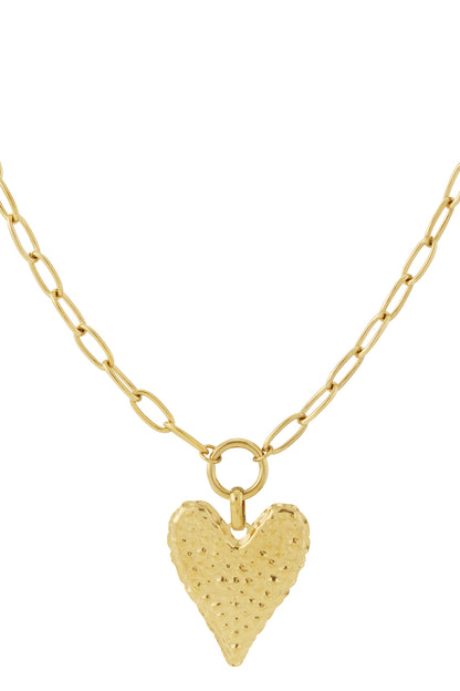 Close-up of gold-plated necklace with a textured hammered heart pendant on a chain with oval links