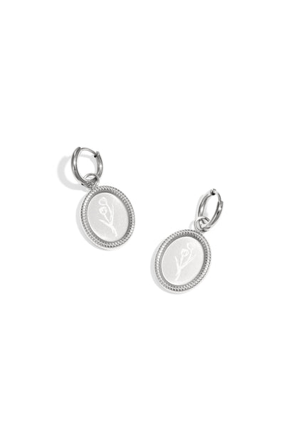 Pair of silver oval hoop earrings with embossed floral design on white background