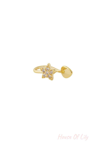 Close-up of gold star-shaped ear and nose cuff with sparkling cubic zirconia stones on a white background
