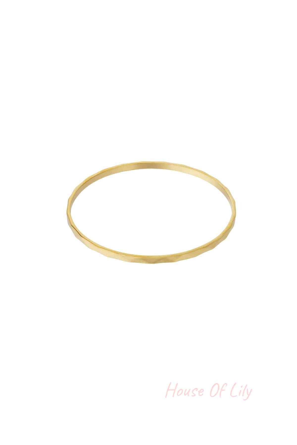 Single thin minimalist hammered gold-tone bangle on white background