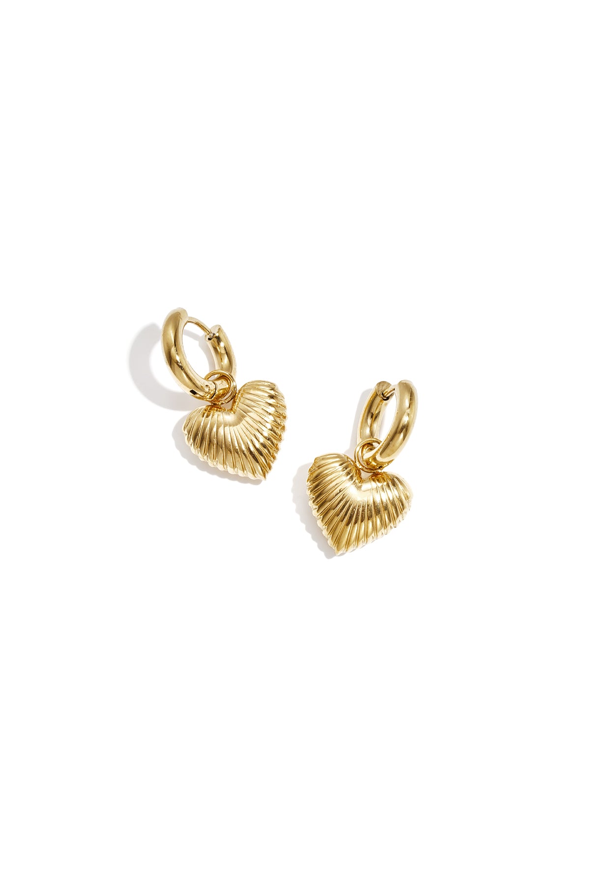 Pair of gold-tone hoop earrings with ribbed heart-shaped drop charms on a white background
