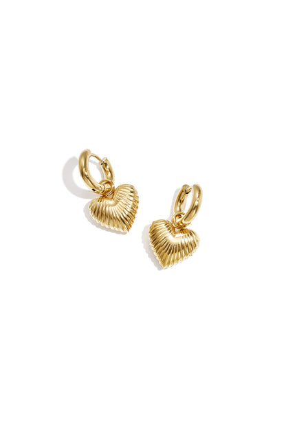 Pair of gold-tone hoop earrings with ribbed heart-shaped drop charms on a white background