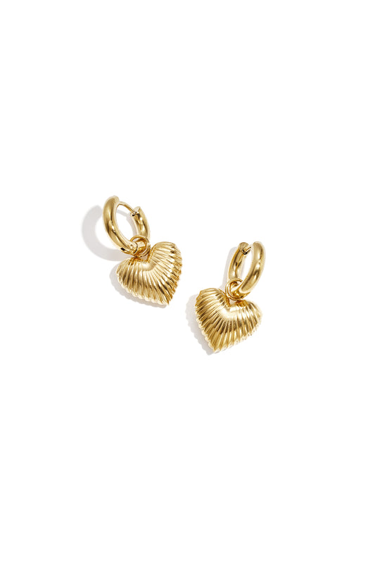 Pair of gold-tone hoop earrings with ribbed heart-shaped drop charms on a white background