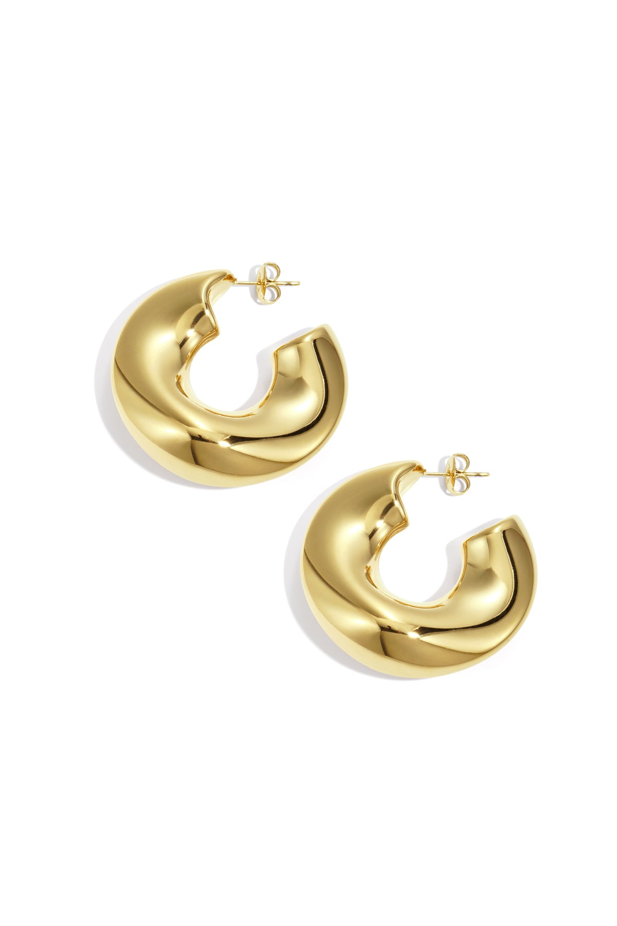 Glossy gold chunky sculptural hoop earrings laid flat on white background
