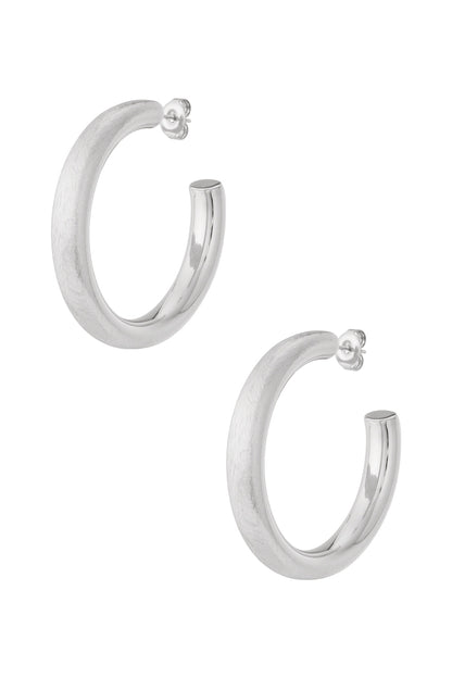 Pair of chunky silver hoop earrings with half matte and half polished finish displayed on white background