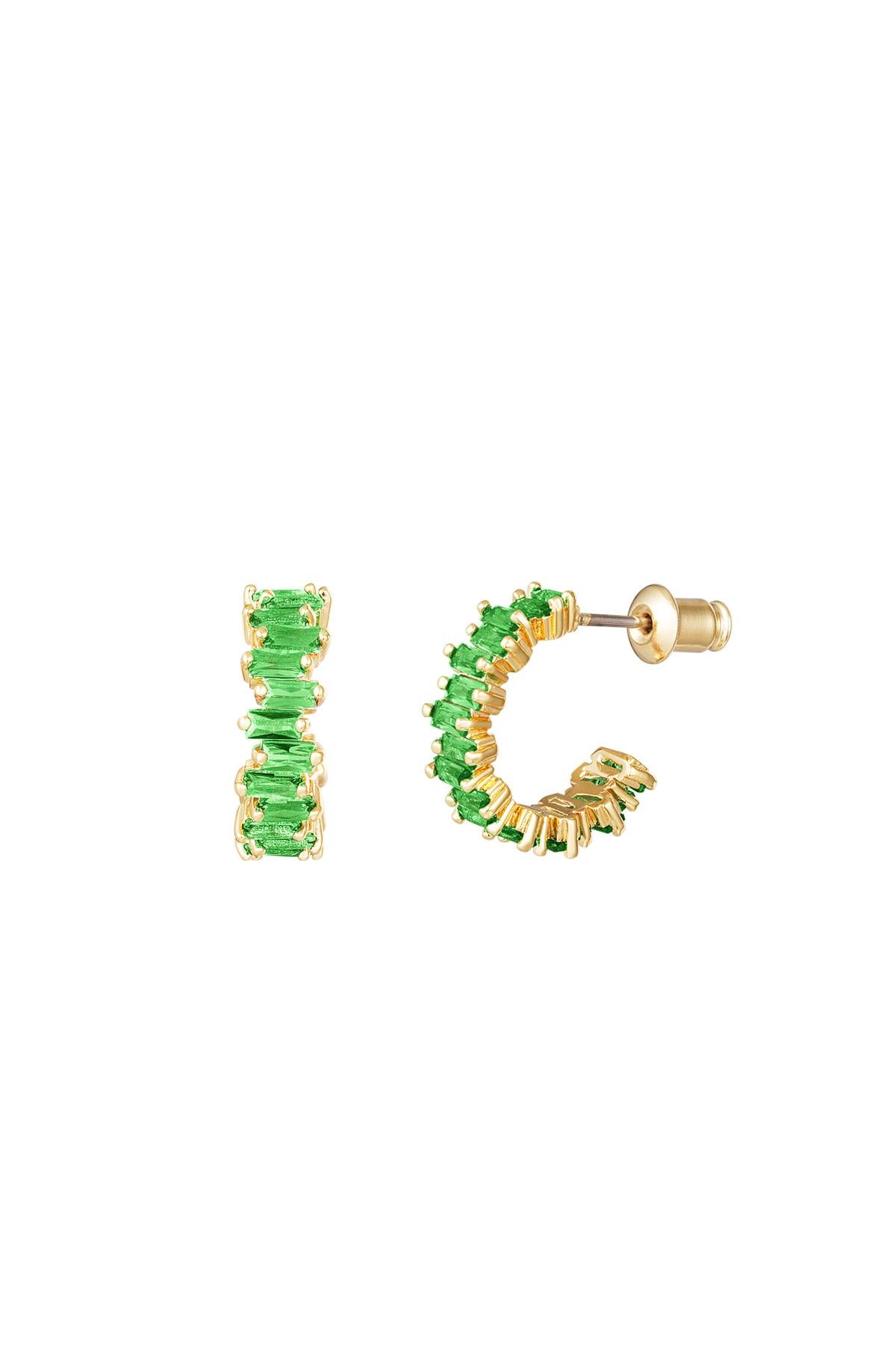 Close-up of a woman's ear wearing pink baguette crystal hoop earrings stacked with textured gold hoops
