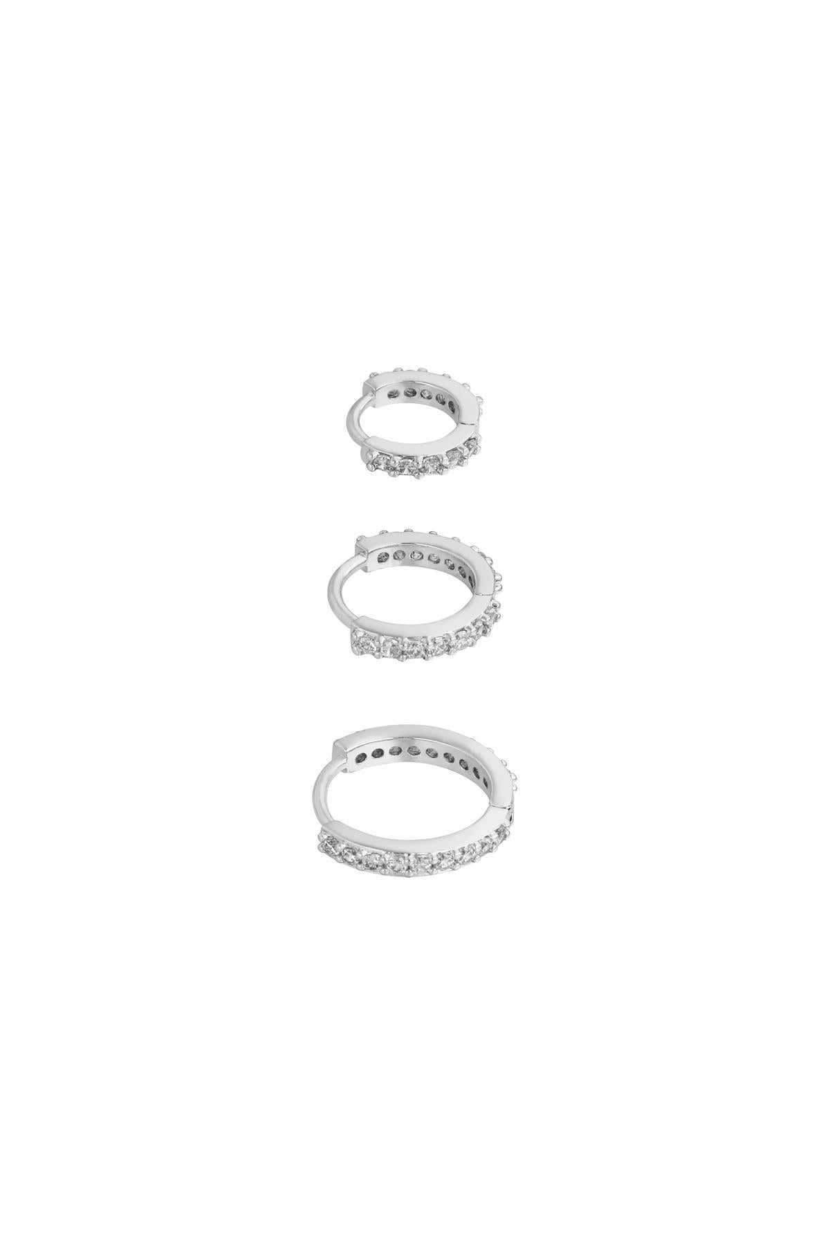 Three silver-tone hoop earrings lined with sparkling clear stones in small, medium, and large sizes on white background