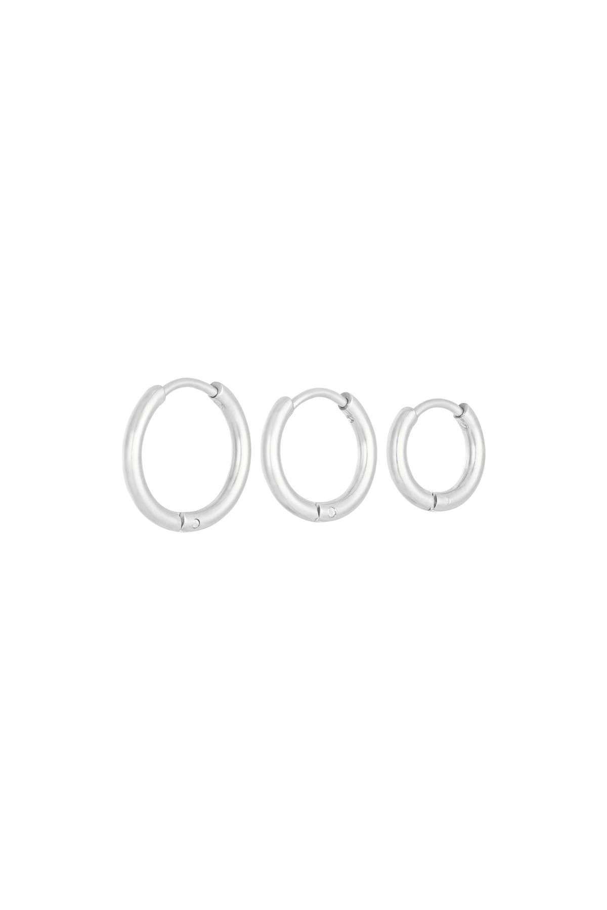 Three silver stainless steel hoop earrings of different sizes lined up on a white background