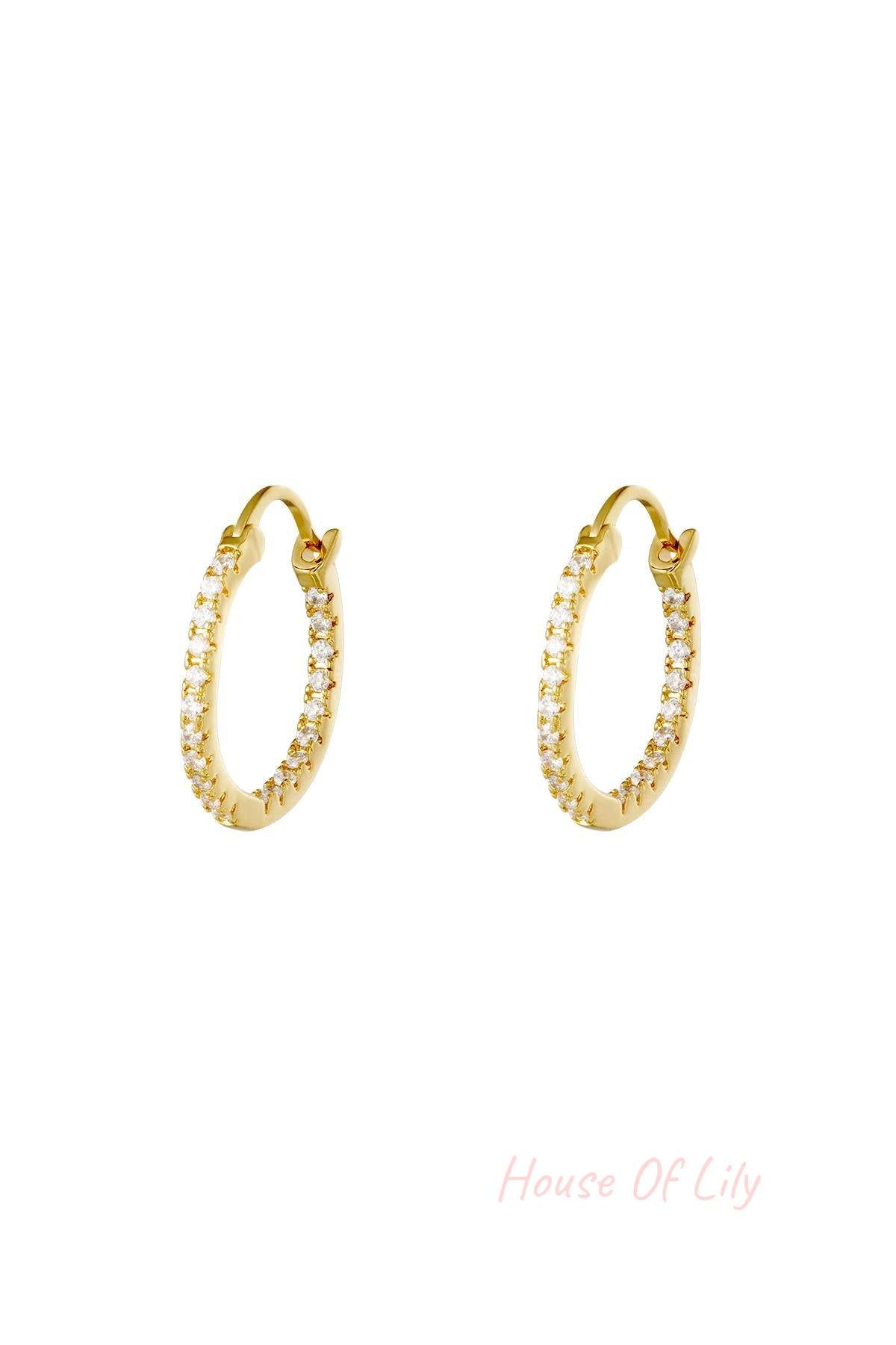 Pair of gold hoop earrings studded with clear stones on white background