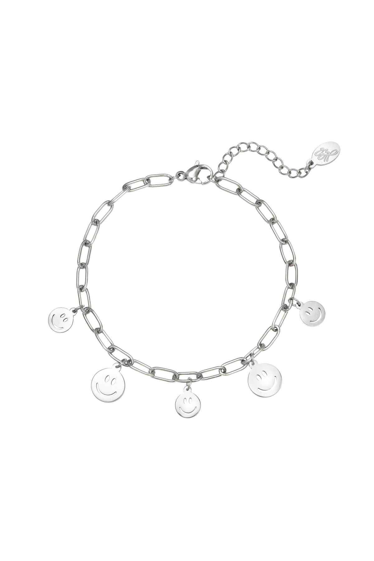 Silver tone link chain bracelet with five dangling smiley face charms and lobster clasp on white background