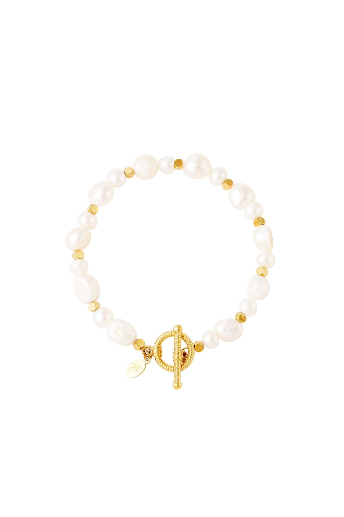 Close-up of a pearl beaded bracelet with gold-tone beads and a decorative toggle clasp on a white background
