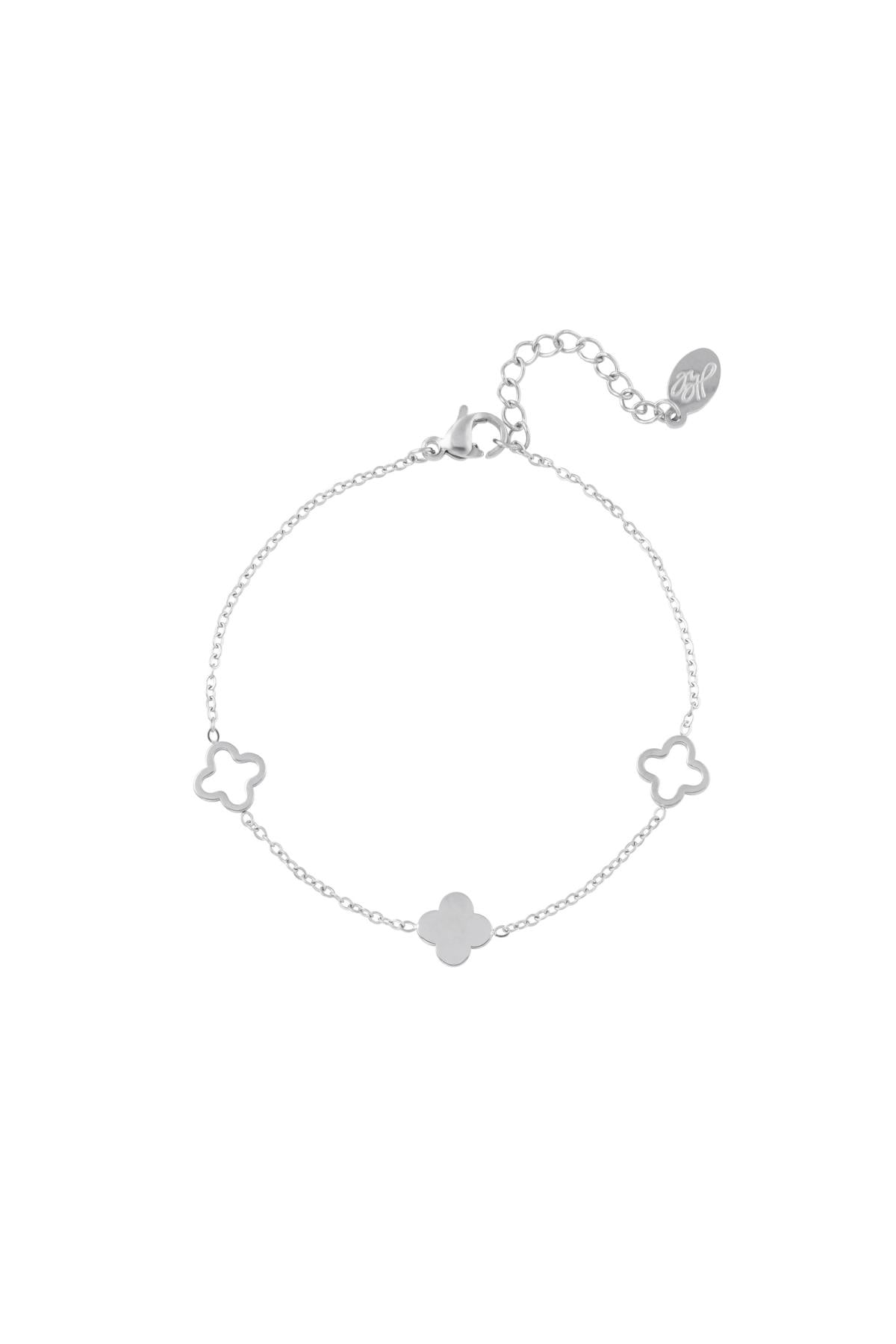 Silver clover charm bracelet with adjustable chain laid flat on a white background