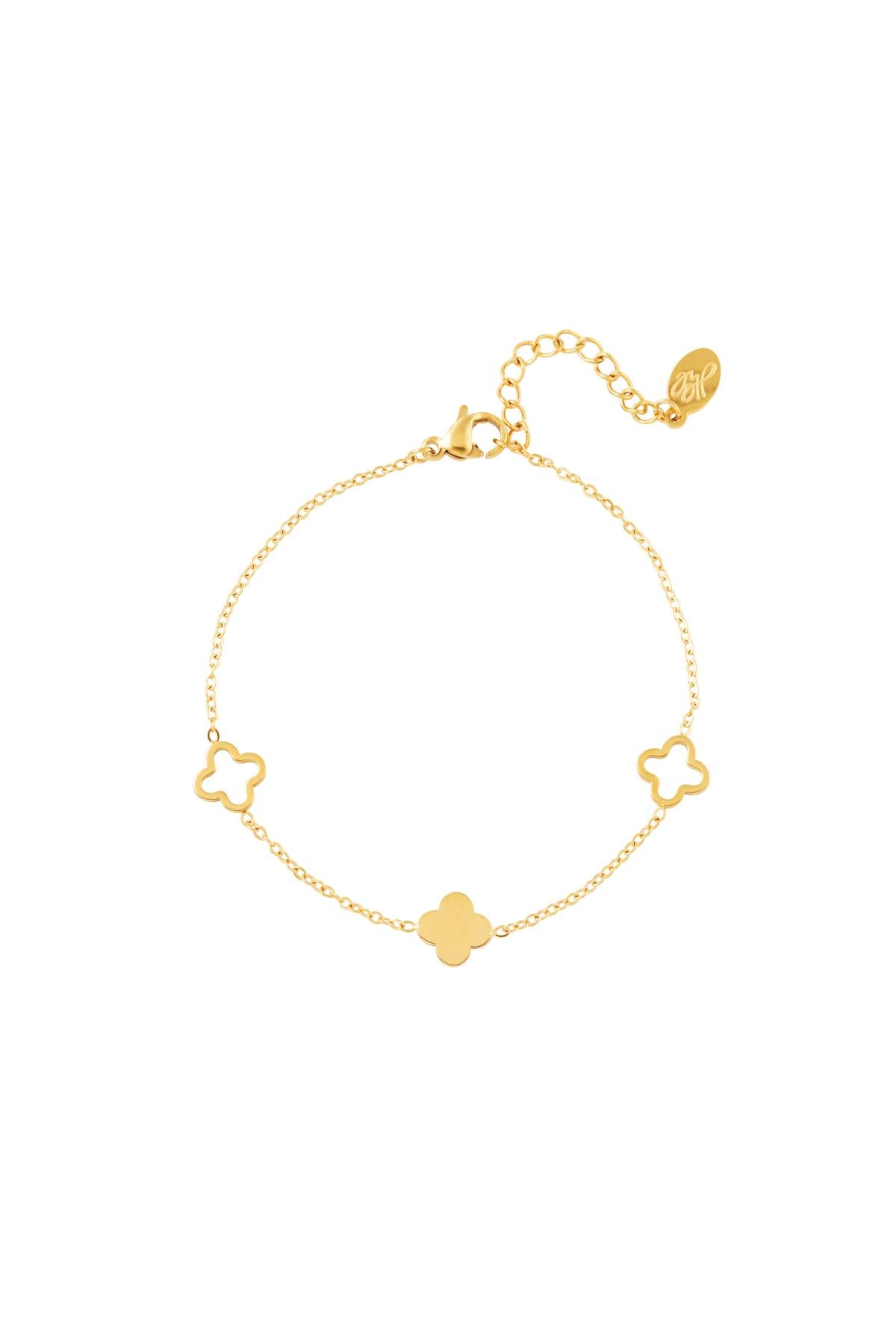 Gold clover charm bracelet with adjustable chain laid flat on a white background