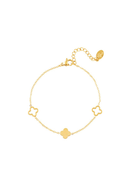 Gold clover charm bracelet with adjustable chain laid flat on a white background