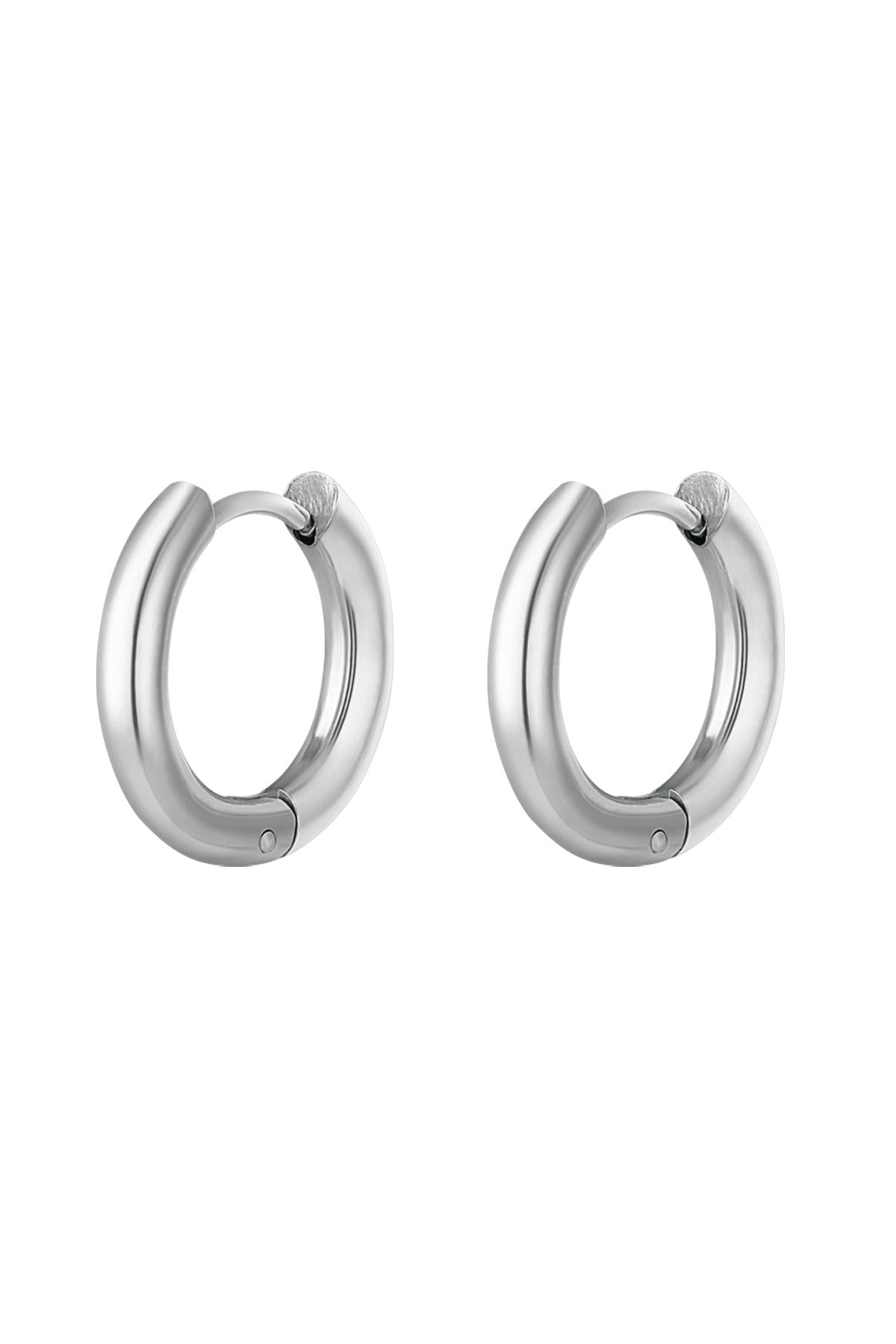 Pair of polished silver-colored stainless steel hoop earrings with rounded smooth design on white background