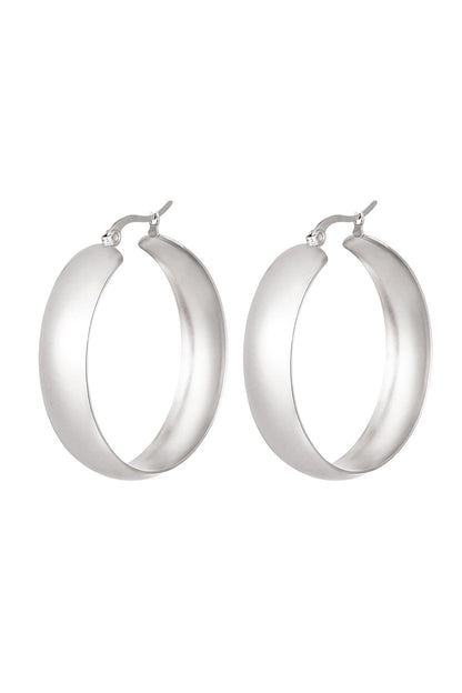 Pair of bold, wide silver hoop earrings with a smooth curved design on a white background